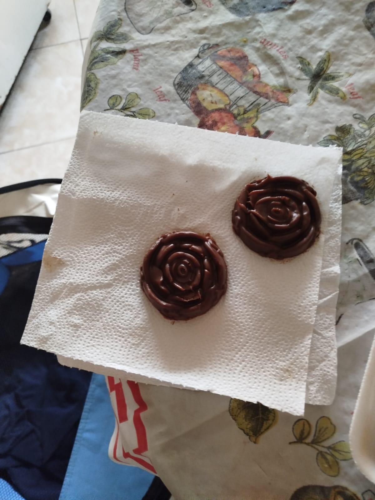 Dos galletas de chocolate en espiral sobre una toalla de papel blanca cuadrada, colocada sobre un mantel estampado.