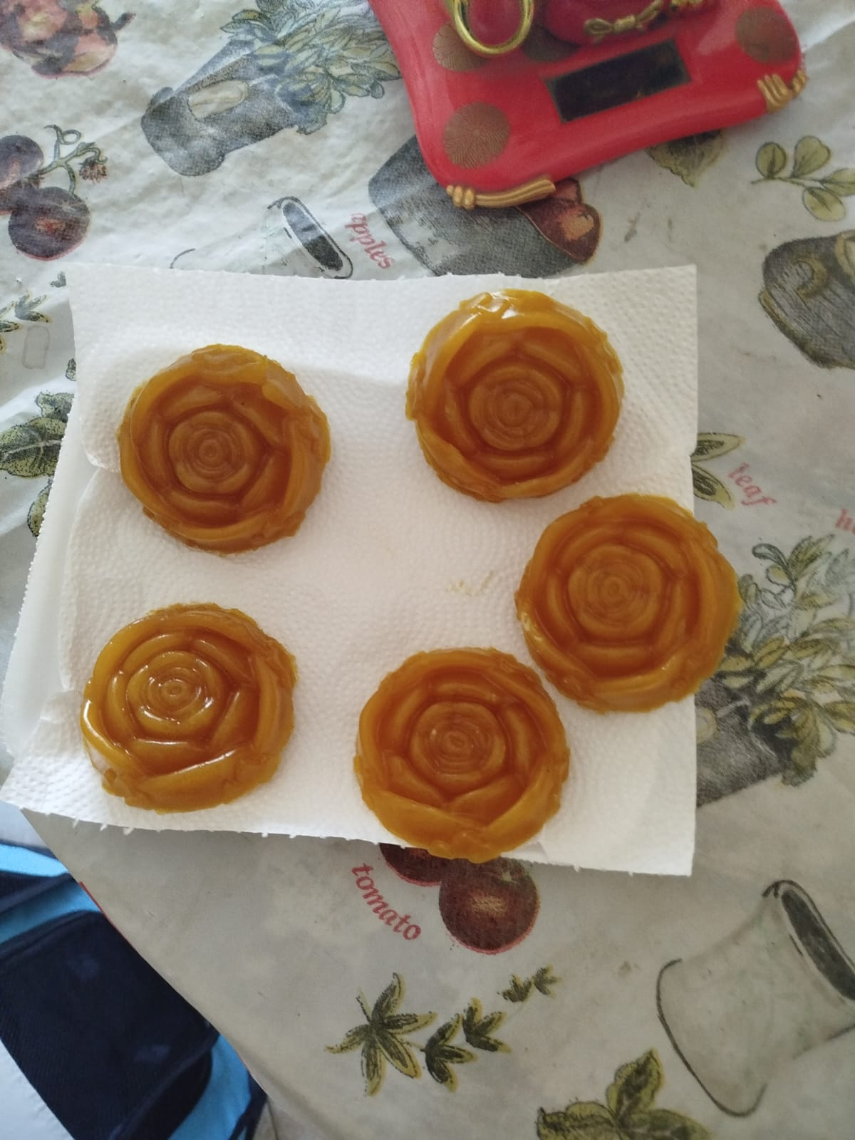 Cinco postres en forma de flores sobre una toalla de papel blanca, colocados sobre un mantel floral.