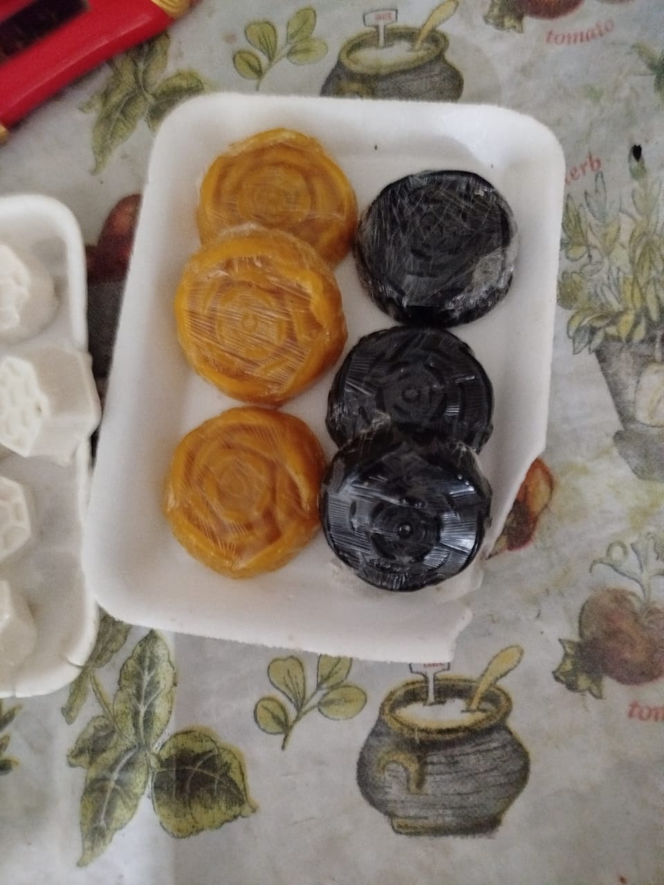 Seis quesos redondos en un recipiente de poliestireno: tres dorados y tres negros.