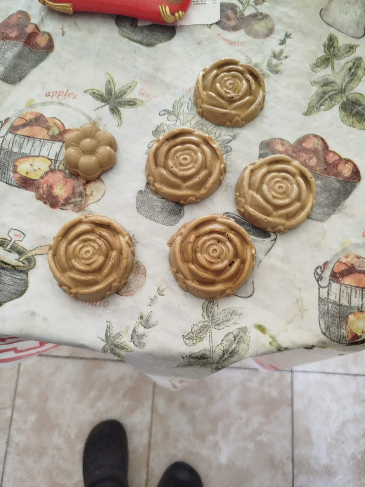 Jabones de color dorado en forma de rosas y flores sobre un mantel con estampado floral.