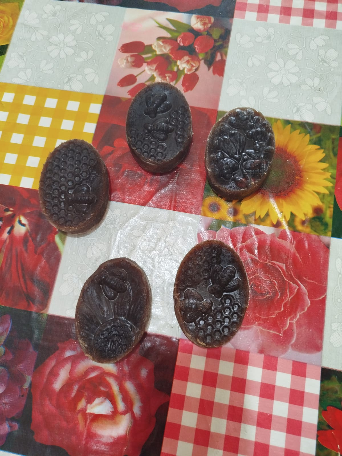 Cinco barras de jabón ovaladas de color marrón oscuro con motivos de panal