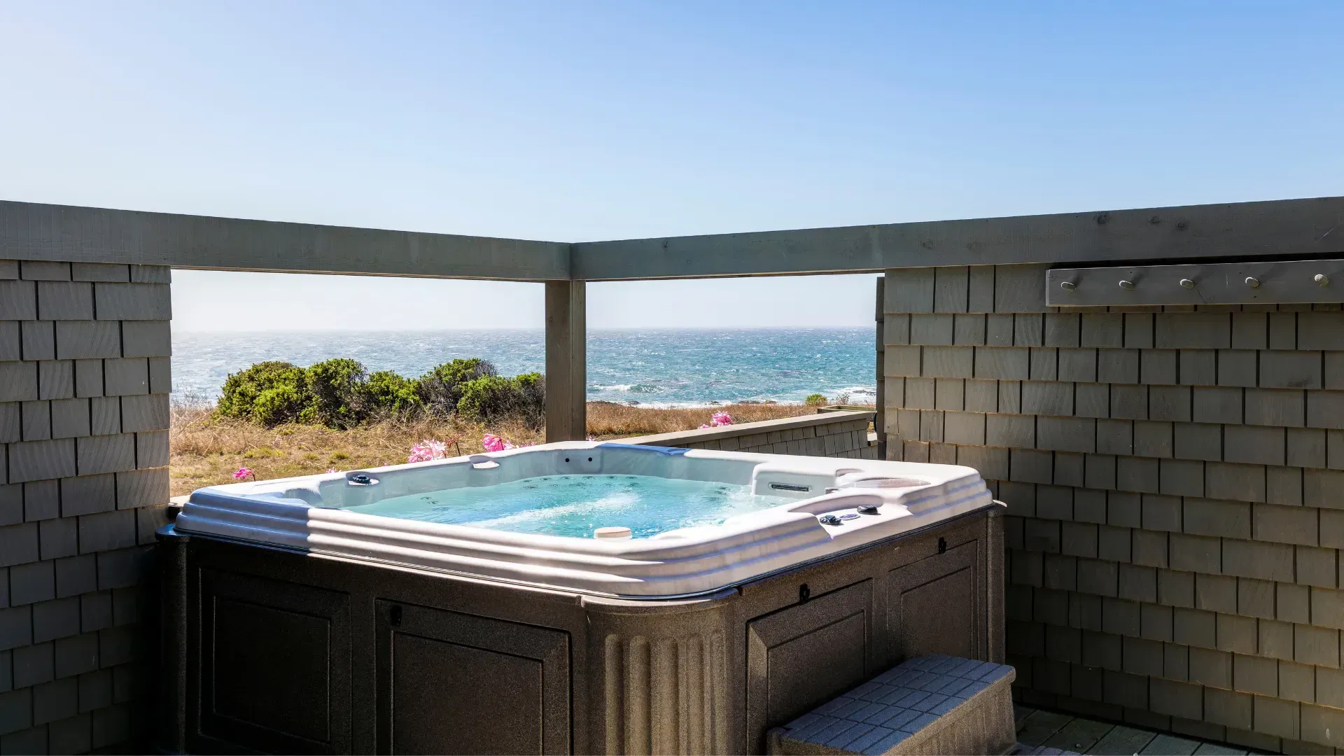 Hot tub with ocean view framed by brick walls.