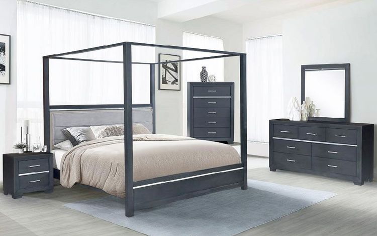 A bedroom with a canopy bed , dresser , nightstand and mirror.