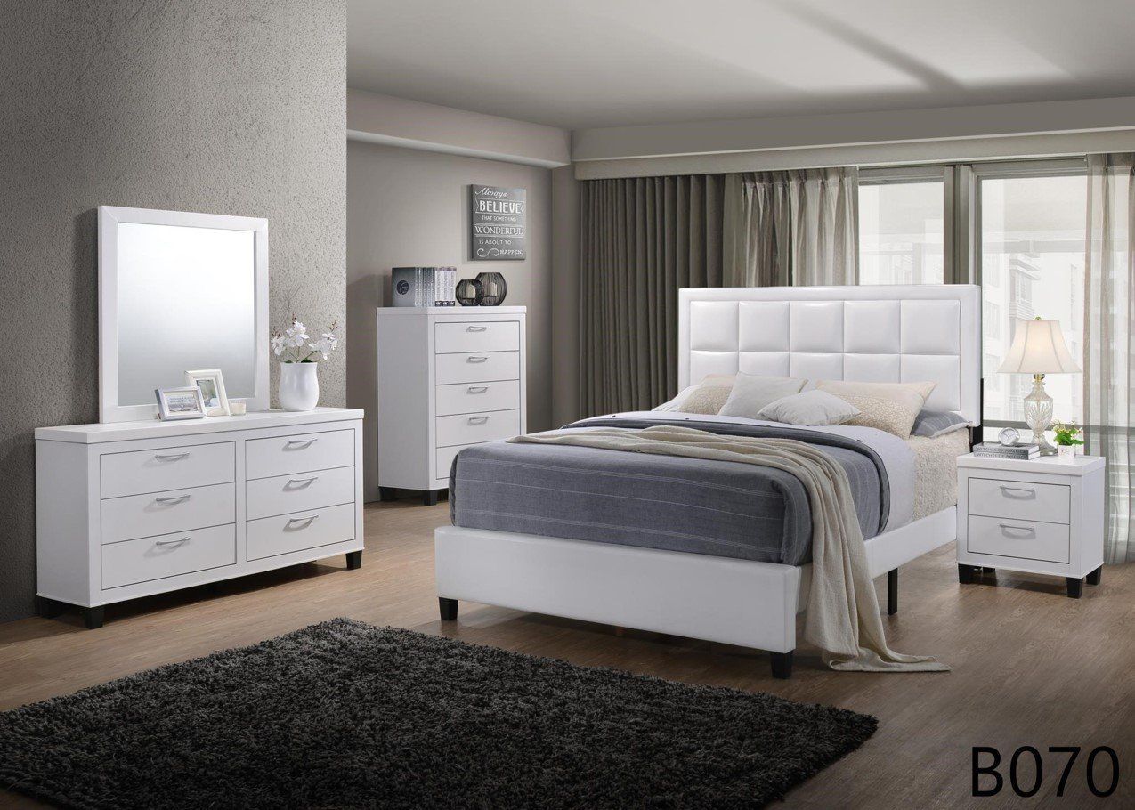A bedroom with a bed , dresser , nightstand , mirror and rug.