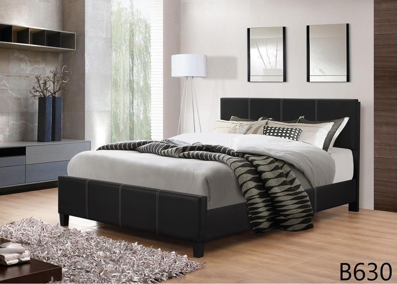 A bedroom with a black bed and a rug