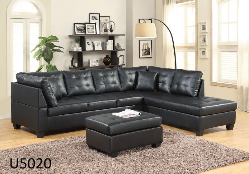 A living room with a black sectional couch and ottoman