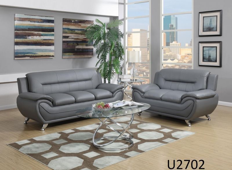 A living room with two grey couches and a glass coffee table