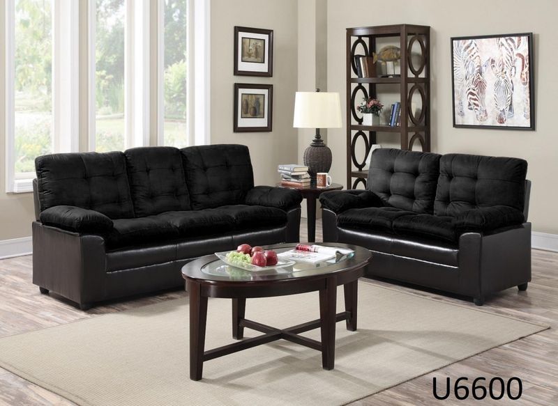 A living room with two black couches and a coffee table