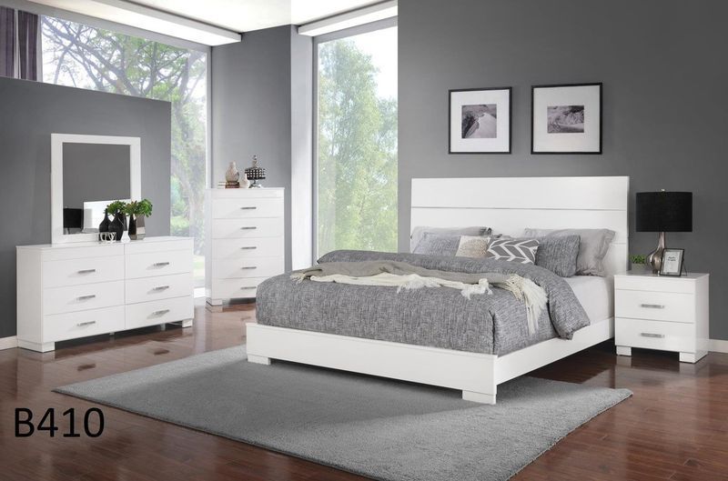 A bedroom with a bed , dresser , nightstand , mirror and rug.