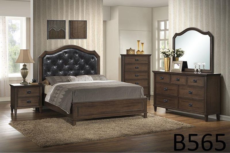 A bedroom with a bed , dresser , nightstand and mirror.