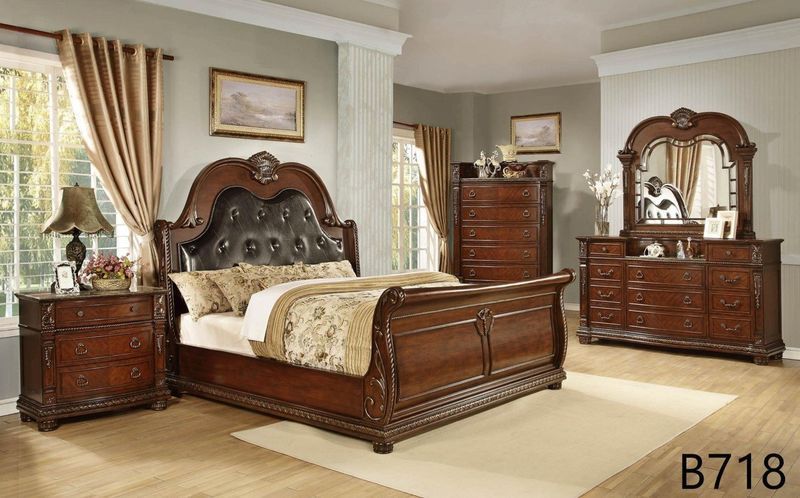 A bedroom with a sleigh bed , dresser , nightstand and mirror.
