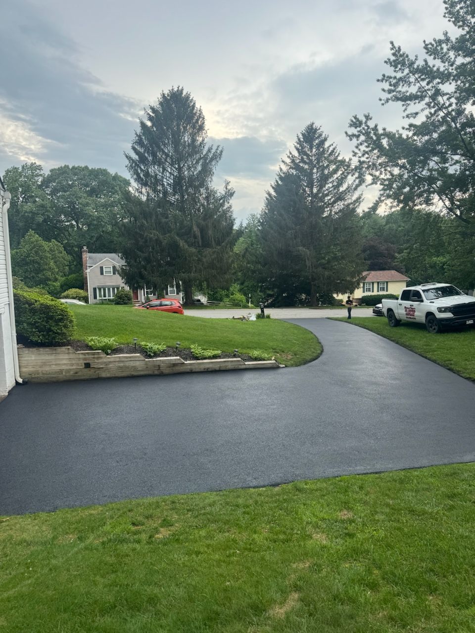 A black driveway with a white truck parked on the side of it.