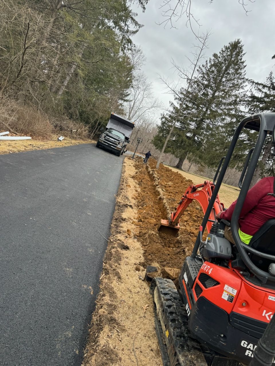 A man is driving an excavator down a dirt road.