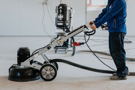 A man is using a grinder on a concrete floor.