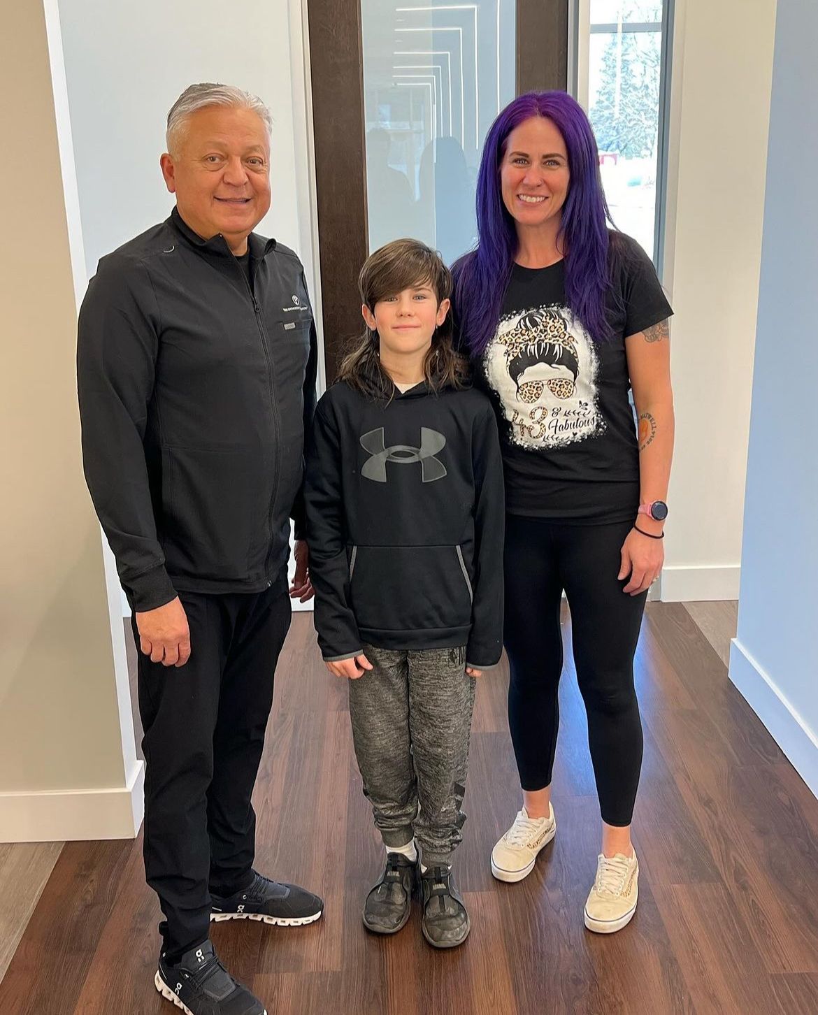 a man , woman and child are posing for a picture in a hallway .