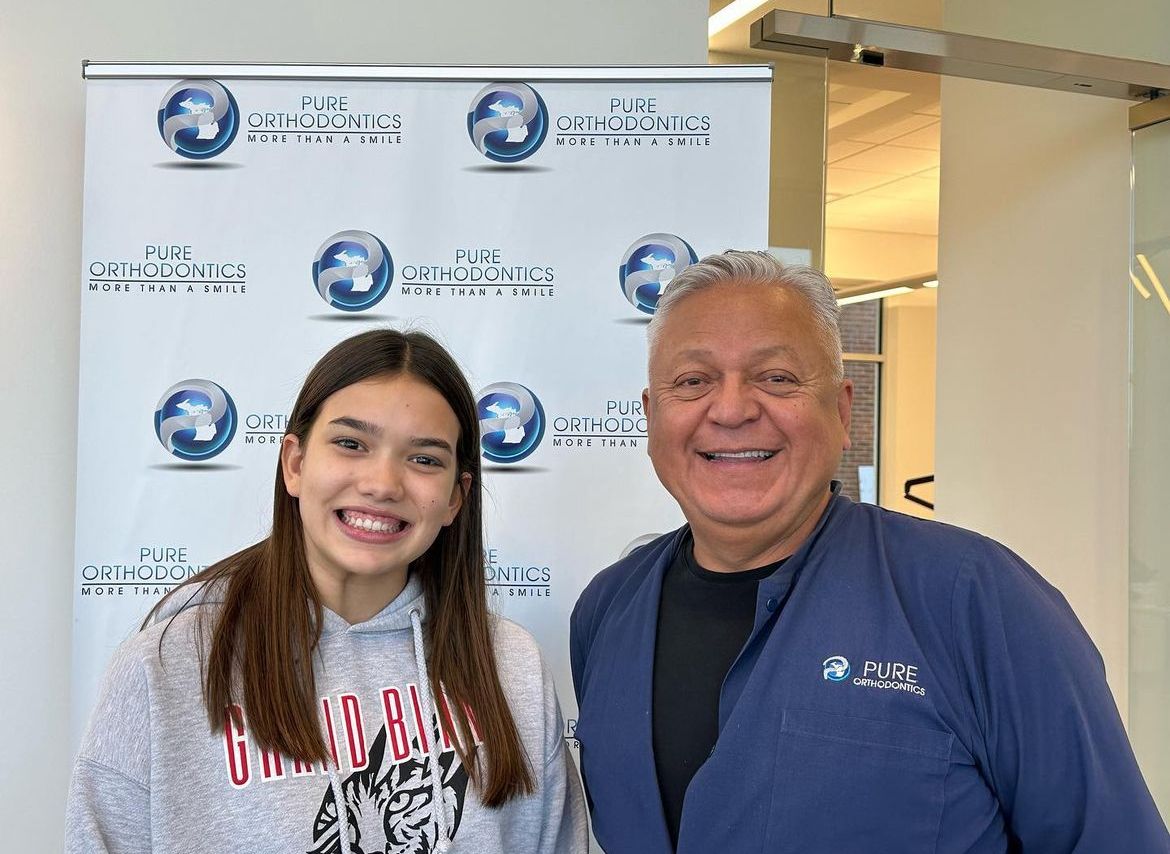 a man and a girl are posing for a picture in front of a banner .