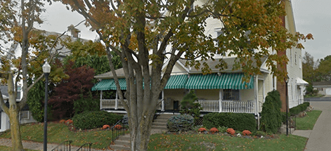 A white house with a green awning on the front porch.