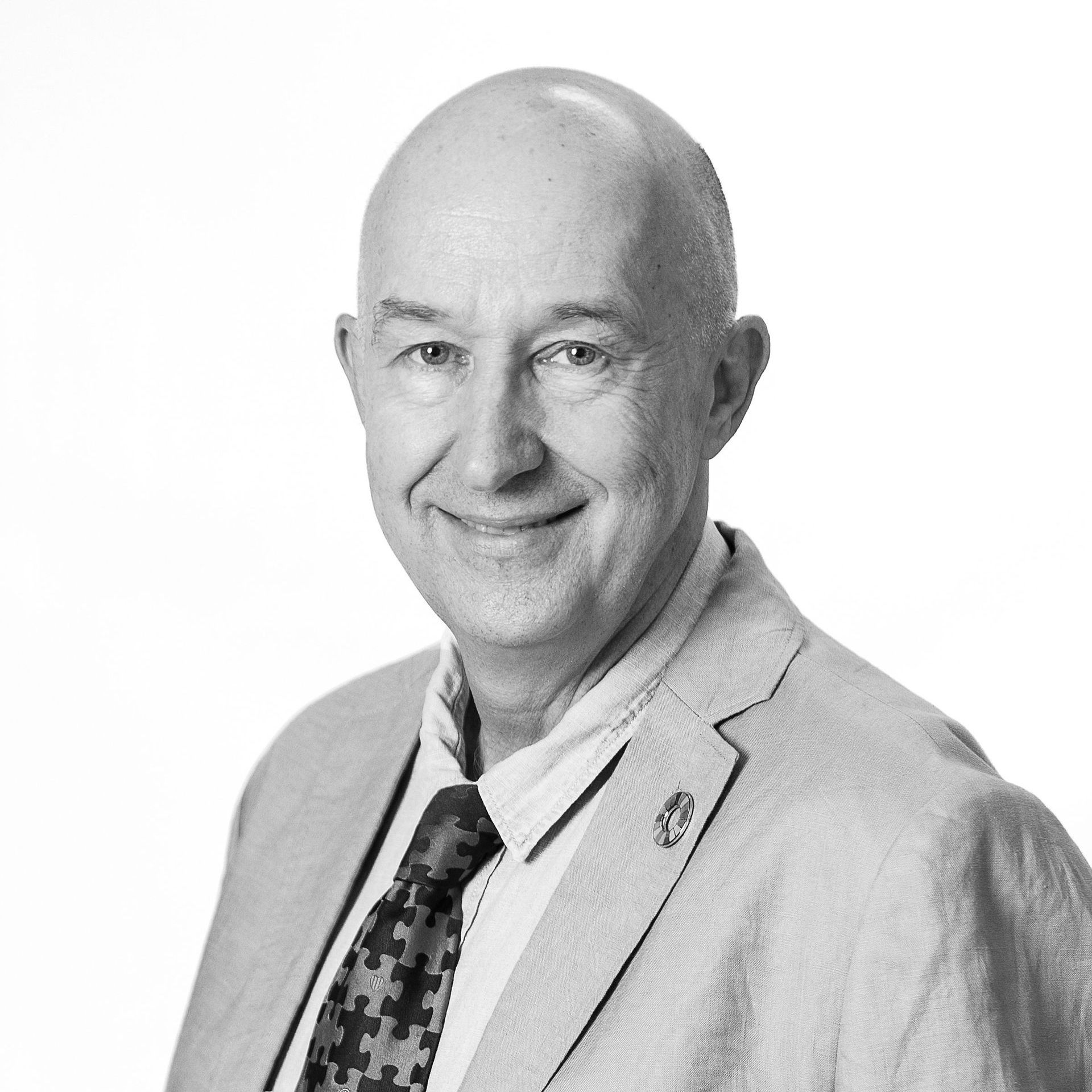 A man in a suit and tie is smiling in a black and white photo.