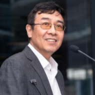 A man in a suit and pink shirt is smiling for the camera.