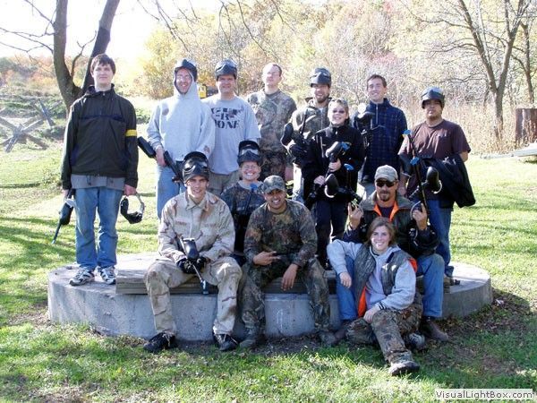 Group of people posing outdoors on a concrete platform in a park with trees in the background