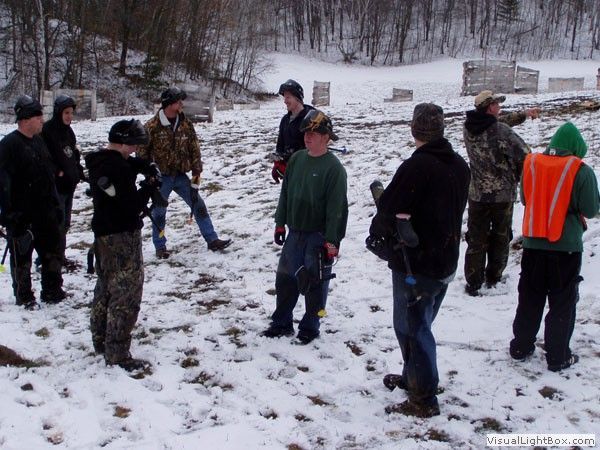 People standing in a snowy outdoor field with shovels and winter clothing