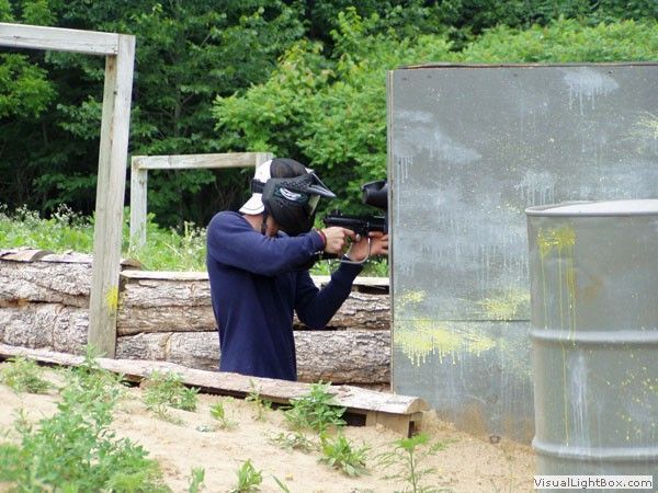 Person aiming a rifle at an outdoor shooting range behind a concrete barrier.