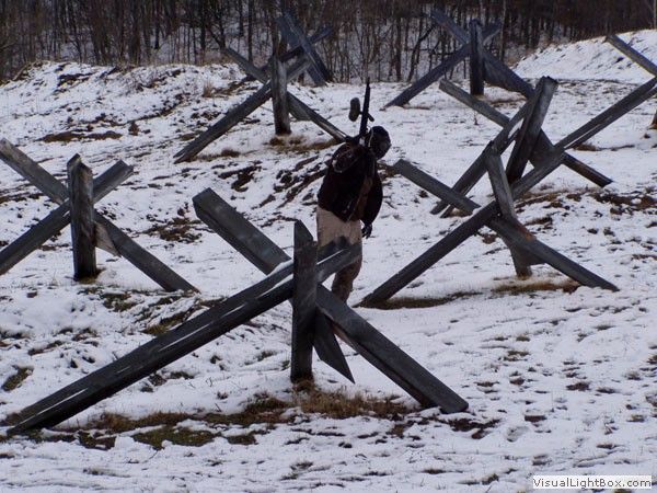 Person standing among WWII-style anti-tank obstacles in a snowy outdoor field