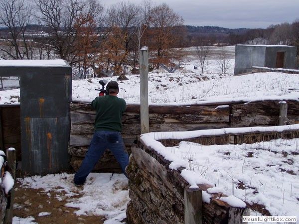 Person aiming a rifle at an outdoor range in a snowy field