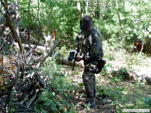 Person in camouflage holding a chainsaw in a dense wooded area