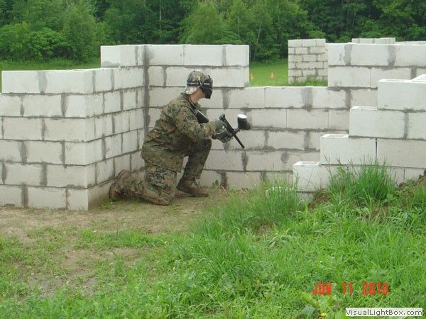 Soldier crouching behind white block walls in a grassy outdoor training area