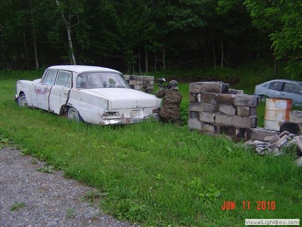 Old white pickup truck parked beside stacked cinder blocks on a grassy roadside