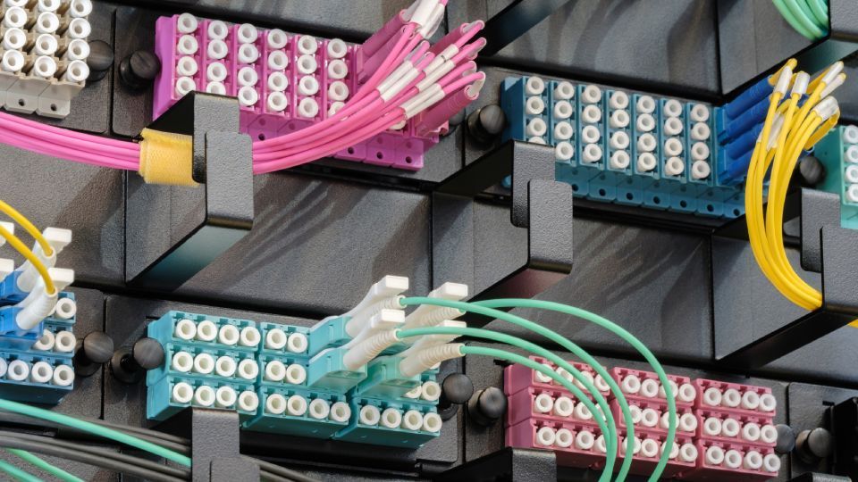 Fiber optic cables connected to distribution panels. Various colored cables and panels, close-up shot.