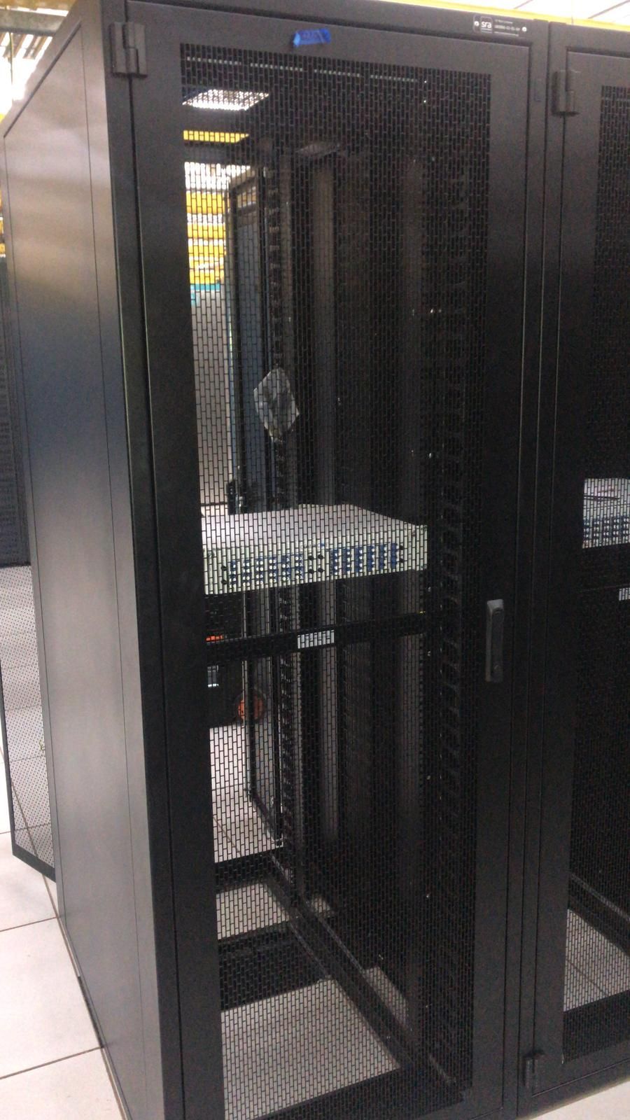 Person attaching cable to a white wireless antenna mounted on a pole, city background.