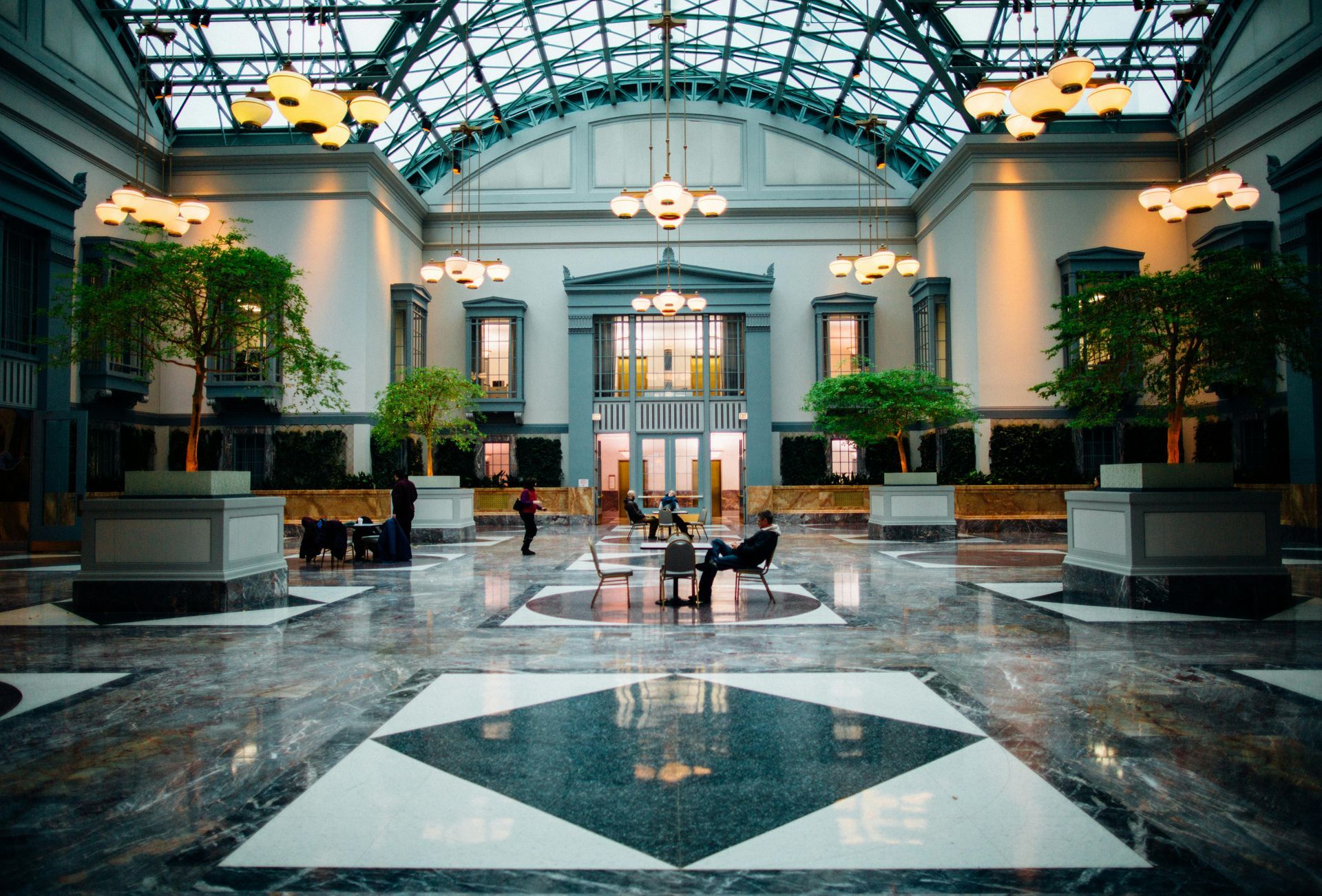A large lobby of a building with people sitting on chairs.