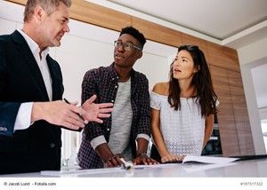 A man is talking to a woman and a man in a kitchen.