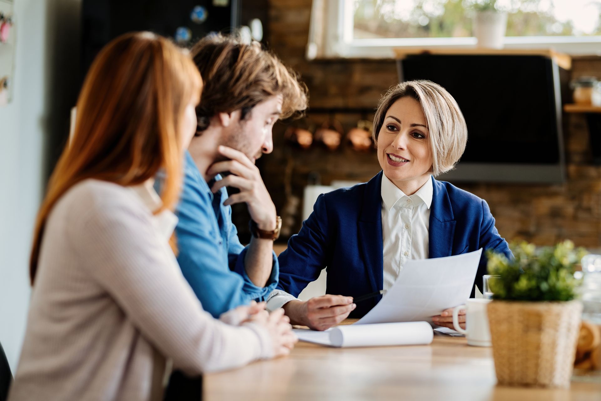 A woman is sitting at a table talking to a man and woman.