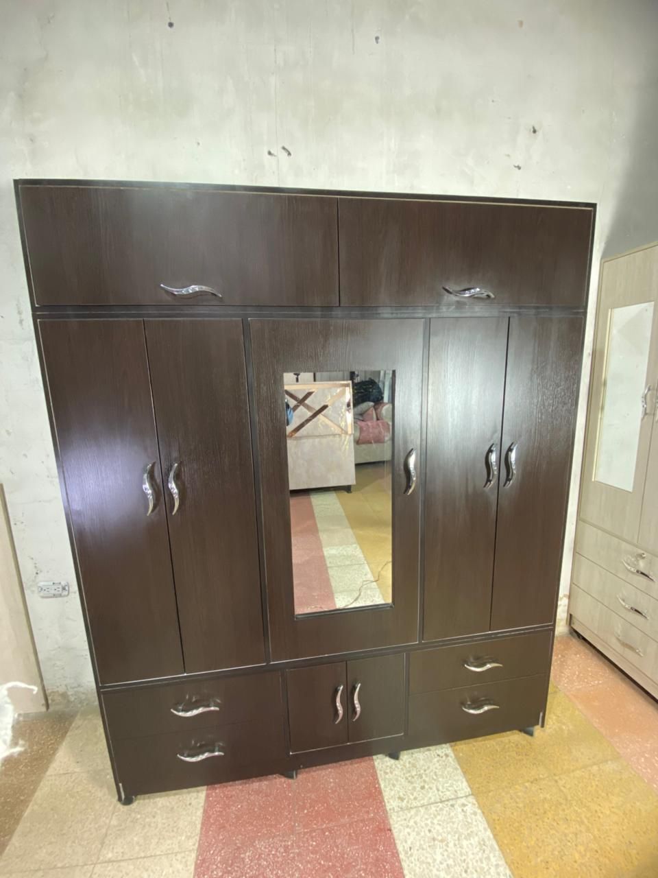 Armario de madera de color marrón oscuro con espejo y cajones.