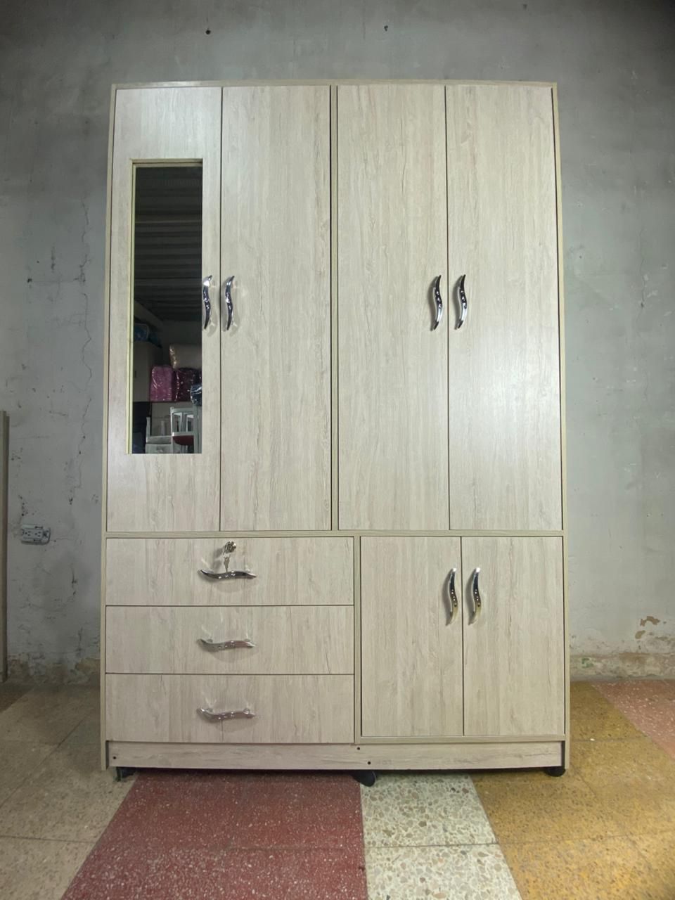 Armario de madera clara con espejo, cajones y puertas de armario contra una pared neutra.