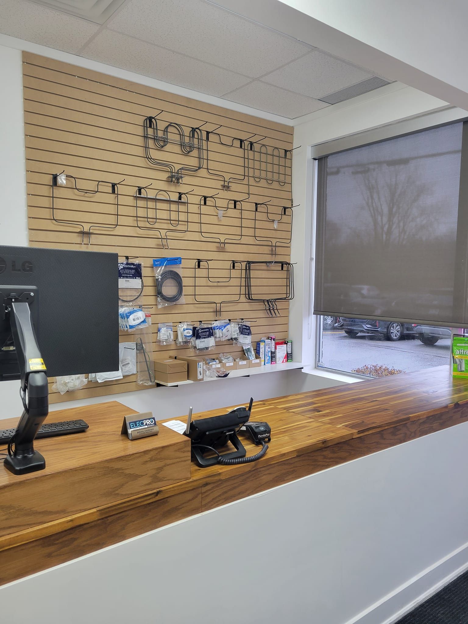 Un écran d'ordinateur est posé sur un bureau en bois devant une fenêtre.