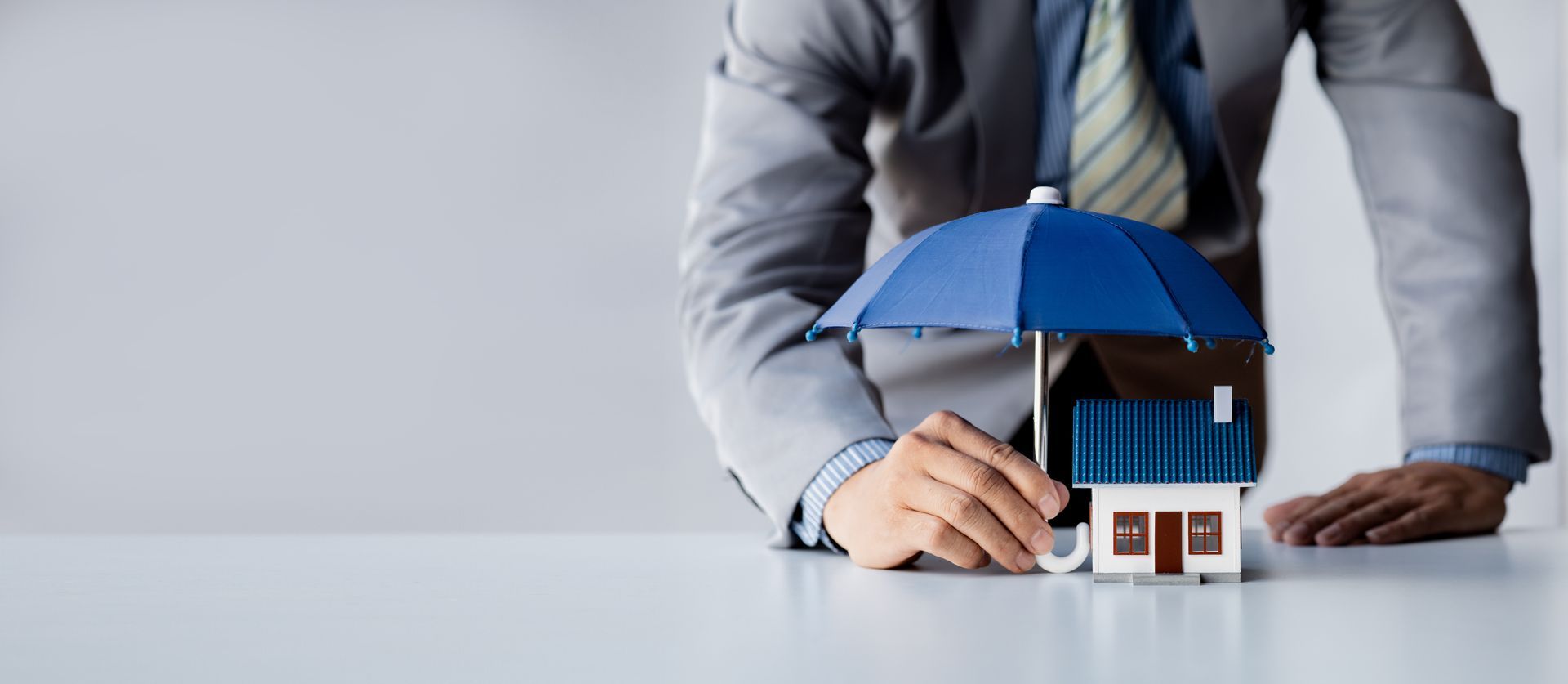 Individual holding a small umbrella and model home.