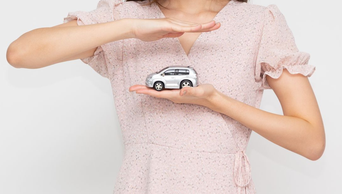 A close-up of a woman holding a red toy car, symbolizing an auto insurance agent.