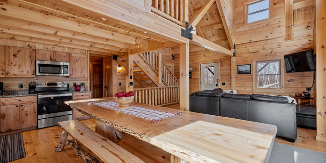 An open-concept log cabin interior featuring a long wooden dining table in Big Bear Lake