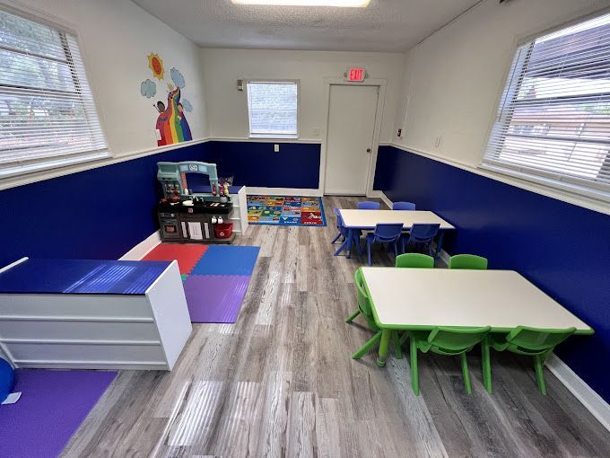 A classroom with tables and chairs and a play area.