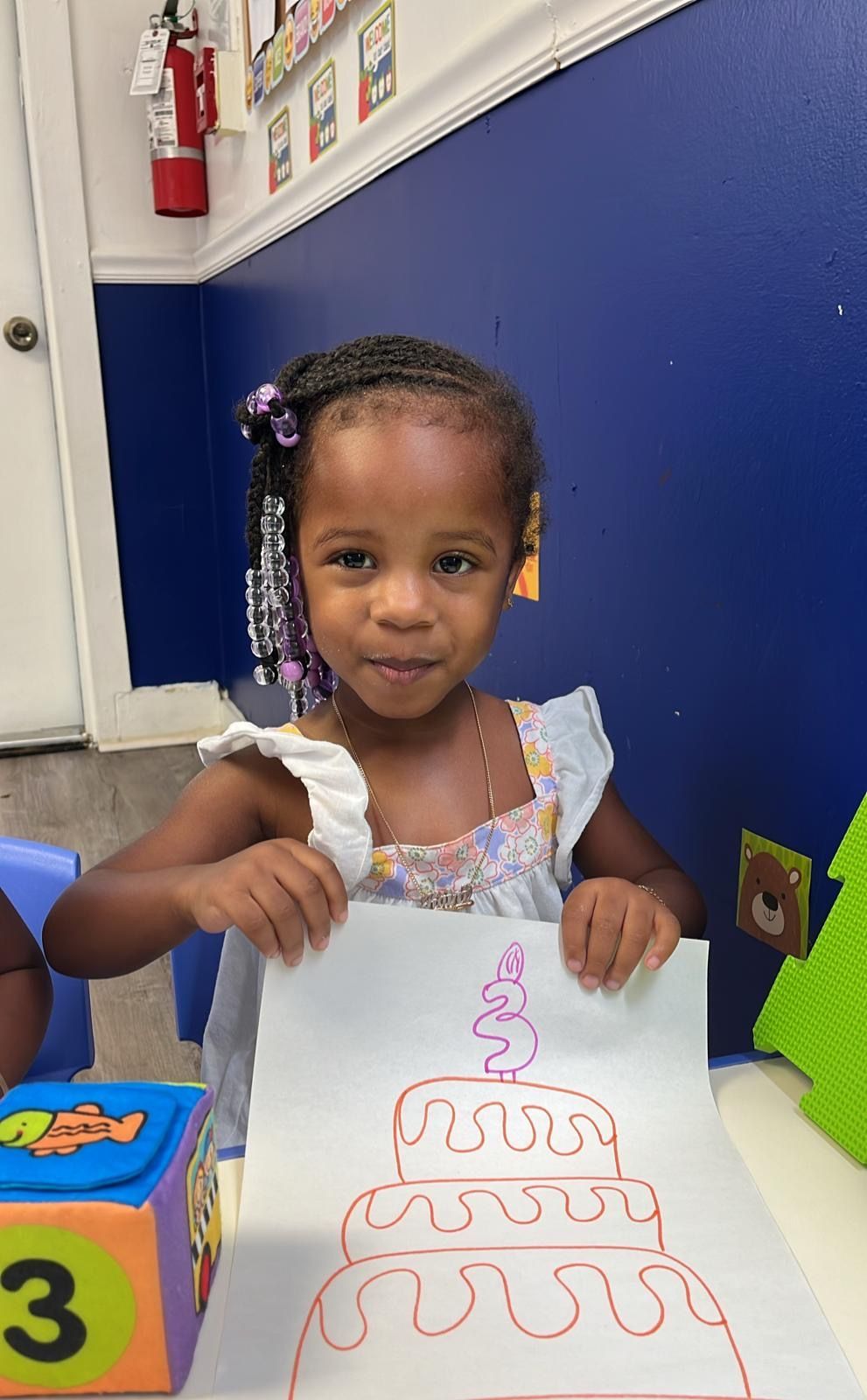 Crafts on a table in a classroom. Paper plate animal figures, with brown and green accents, sit on a wooden table.