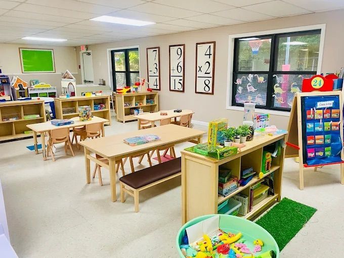 Bright classroom with wooden furniture, educational materials, and a calendar.