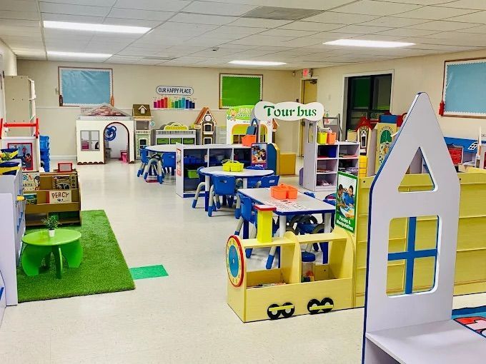 Brightly lit, colorful preschool classroom with tables, toys, and learning stations.