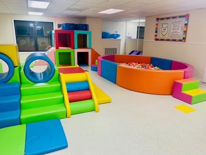 Playroom with colorful foam climbing blocks, tunnel, and ball pit.