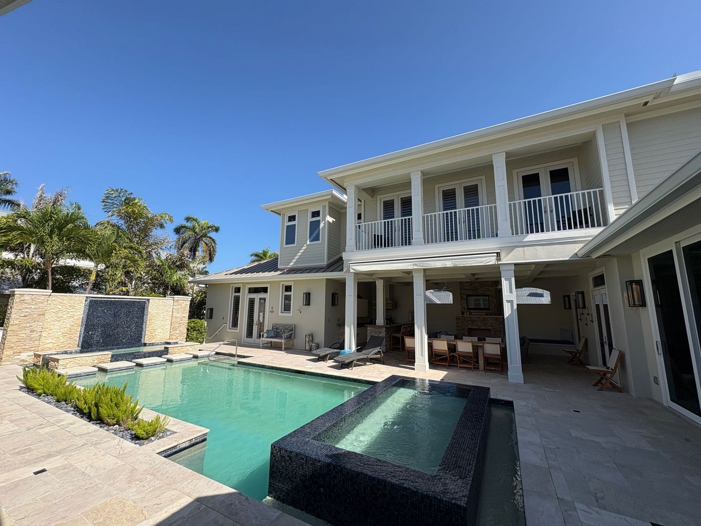 Large house with a pool, spa, and outdoor dining area; sunny day.