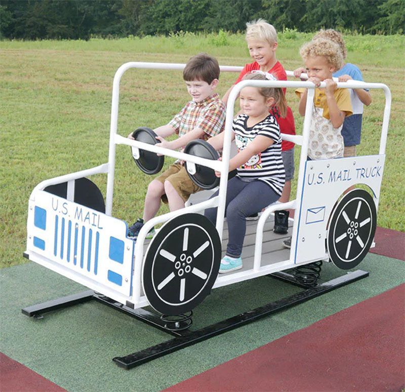 Children playing on a U.S. Mail truck-shaped playground equipment outdoors.