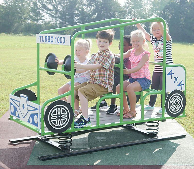 Children playing on a green, spring-mounted play structure shaped like a 4x4 truck.
